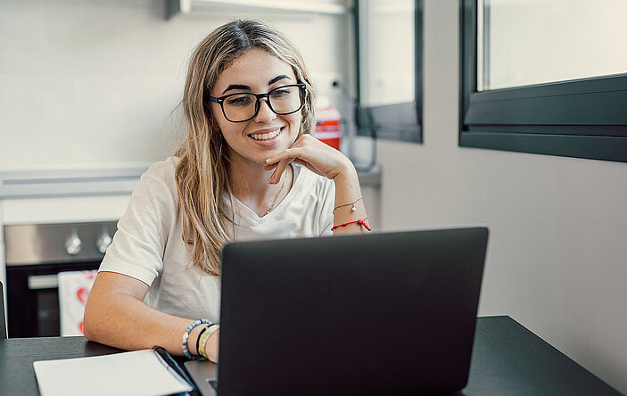 Happy young blonde business woman entrepreneur using computer looking at screen working in internet sit at office desk, smiling millennial female professional employee typing email on laptop workplace